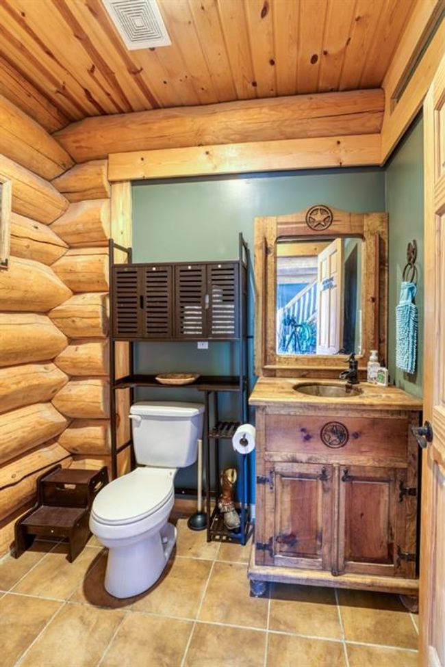Bathroom featuring toilet, wood ceiling, visible vents, and log walls | Image 22