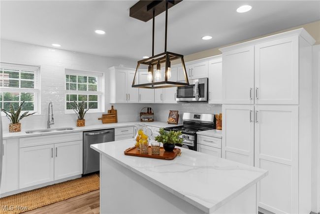 Kitchen featuring appliances with stainless steel finishes, white cabinets, decorative backsplash, light wood-style flooring, and recessed lighting | Image 8