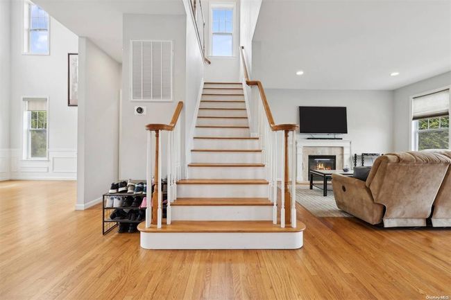 Staircase with wood finished floors, a glass covered fireplace, recessed lighting, and a wainscoted wall | Image 11