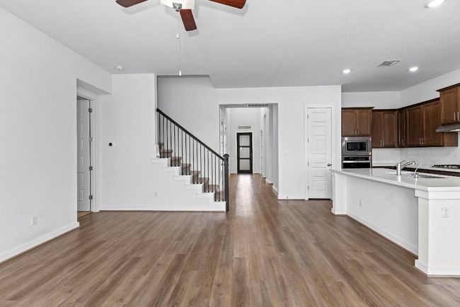 Kitchen with stainless steel appliances, light countertops, a ceiling fan, light wood-type flooring, and a sink | Image 11