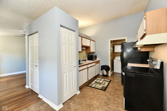 kitchen with light countertops, a sink, under cabinet range hood, and washer / clothes dryer | Image 4