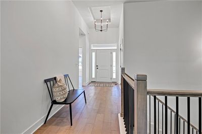 Entrance foyer with a notable chandelier, a high ceiling, light hardwood / wood-style floors, and a raised ceiling | Image 2