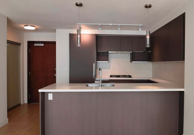 Kitchen with backsplash, a sink, light countertops, a peninsula, and a textured ceiling | Image 11