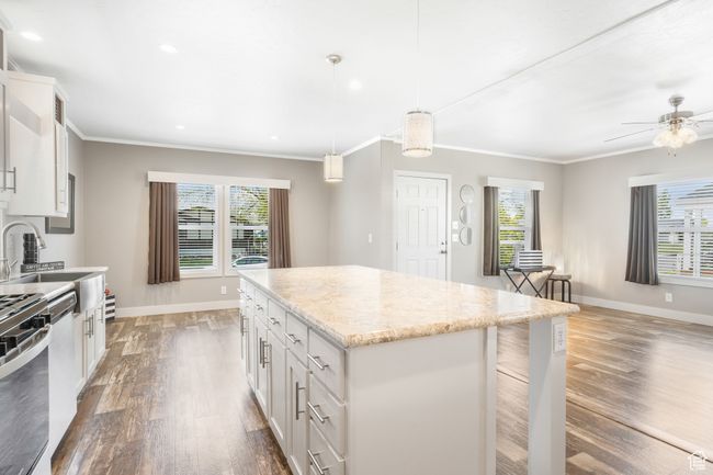 Kitchen featuring baseboards, dark wood-style floors, a kitchen island, white cabinetry, and ornamental molding | Image 4
