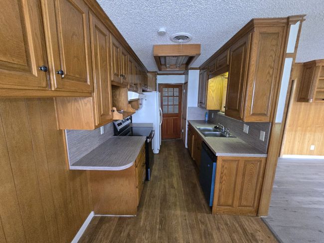 Kitchen featuring electric range, dishwasher, dark wood-style floors, brown cabinetry, and a textured ceiling | Image 15