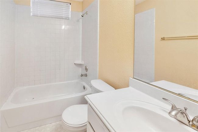 Bathroom featuring bathtub / shower combination, a textured wall, vanity, and toilet | Image 22