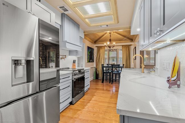 Recently renovated kitchen includes new cabinetry with under cabinet lighting, quartz counters, stainless appliances, breakfast level bar open to living area | Image 5