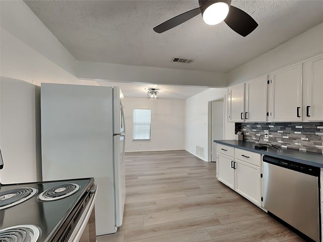 Kitchen featuring dishwasher, dark countertops, a textured ceiling, white cabinets, and ceiling fan | Image 7