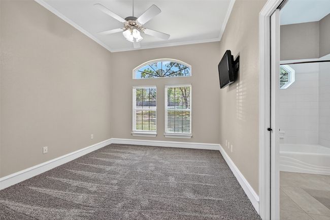 Carpeted spare room featuring crown molding, a ceiling fan, and baseboards | Image 22