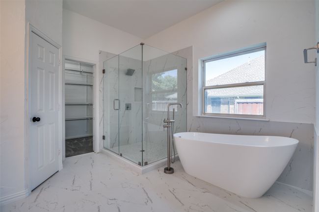 Full bathroom featuring a marble finish shower, a freestanding bath, marble finish floors, and a walk in closet | Image 15