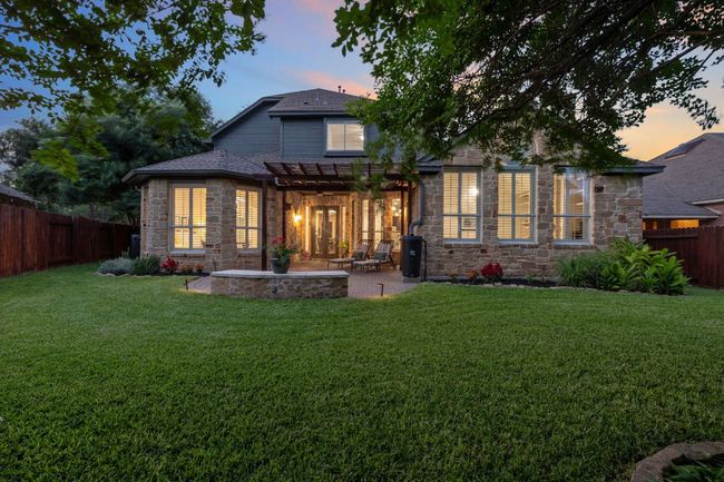 Back of house at dusk with stone siding, a pergola, a patio area, and roof with shingles | Image 29