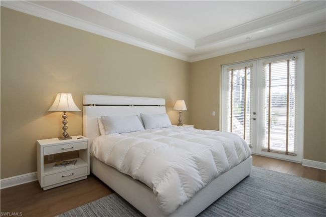 Bedroom with access to outside, wood finished floors, ornamental molding, and a tray ceiling | Image 9