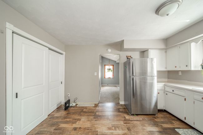 Kitchen with freestanding refrigerator, dark wood-style floors, light countertops, and white cabinets | Image 7