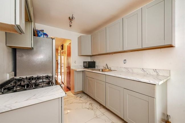 Kitchen featuring range, white refrigerator, sink, gray cabinets, and light tile patterned floors | Image 7