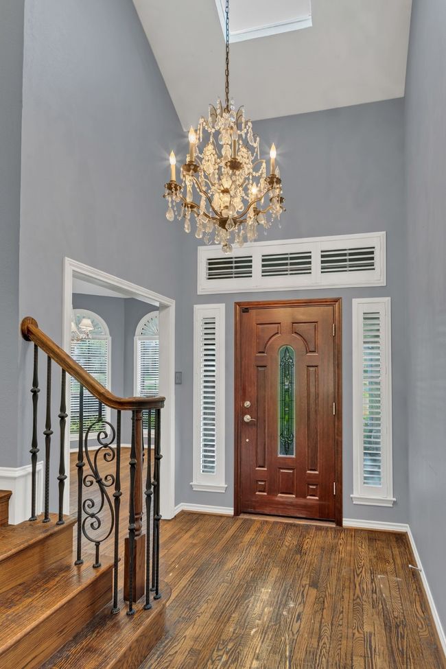Entryway featuring a high ceiling, a chandelier, wood finished floors, and stairway | Image 6
