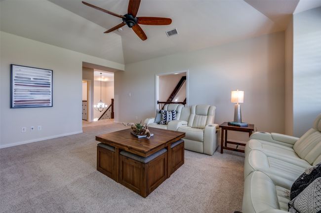 Living room with light carpet, a ceiling fan, vaulted ceiling, and a chandelier | Image 27