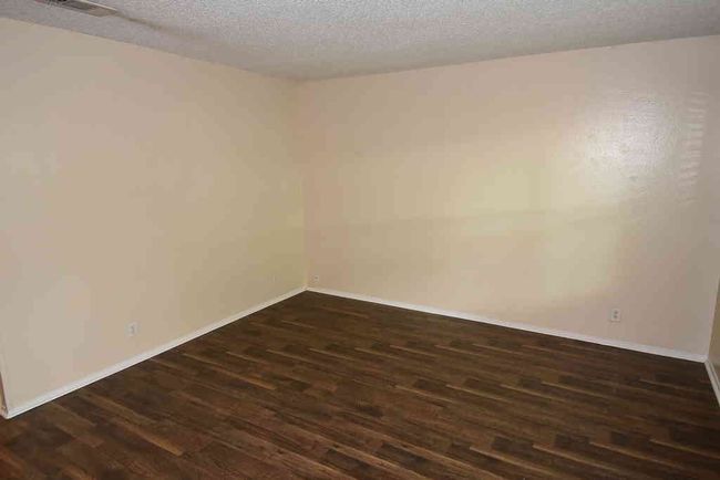 Bedroom featuring dark wood finished floors, a textured ceiling, and baseboards | Image 9