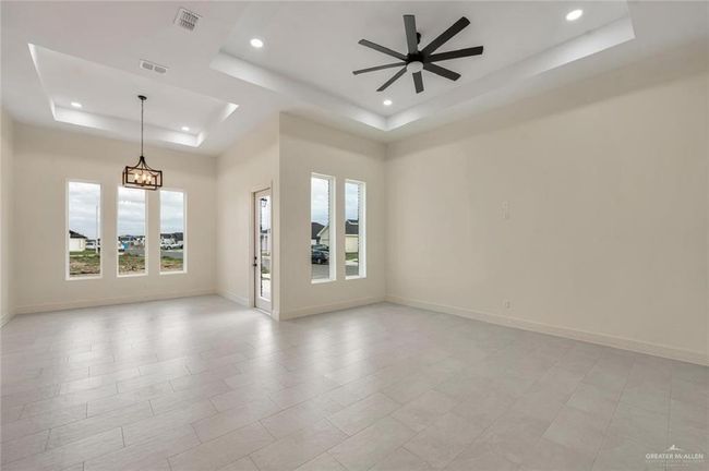 Unfurnished room featuring a raised ceiling, recessed lighting, ceiling fan, a chandelier, and baseboards | Image 7