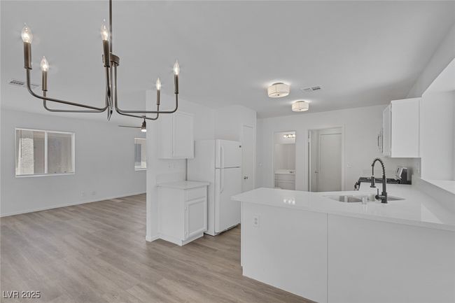 Kitchen featuring freestanding refrigerator, washer / clothes dryer, light countertops, and white cabinetry | Image 4