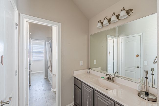 Bathroom with vaulted ceiling, tile patterned flooring, vanity, shower / bath combo with shower curtain, and baseboards | Image 32