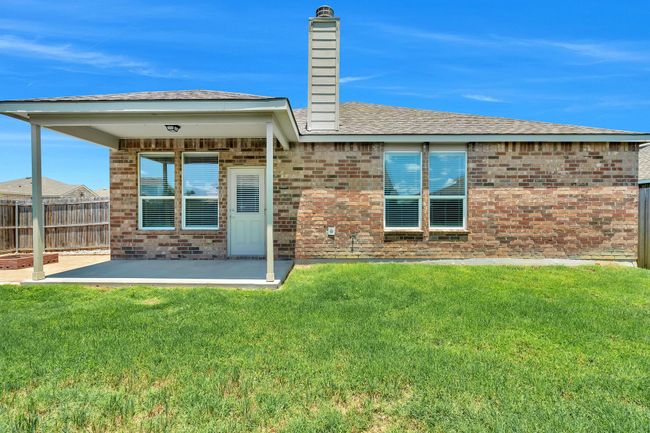 Rear view of property featuring a patio area, a chimney, brick siding, and a shingled roof | Image 28