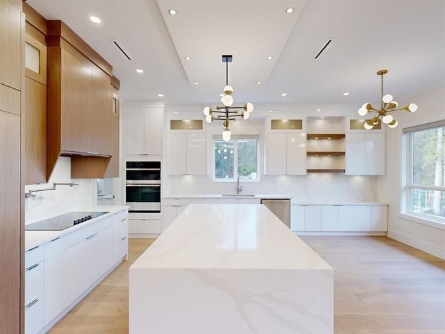 Kitchen with a chandelier, modern cabinets, stainless steel appliances, and recessed lighting | Image 9
