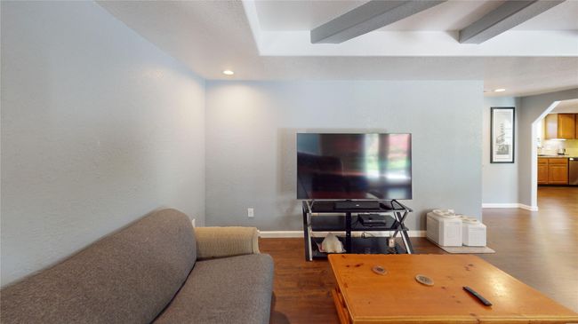 Living room with dark wood finished floors, arched walkways, beamed ceiling, and recessed lighting | Image 5