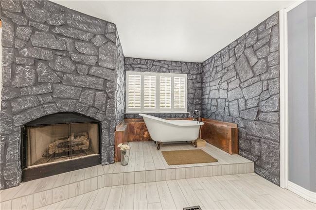 upstairs primary Bathroom featuring a freestanding bath, wood look tile floors, and a fireplace | Image 18