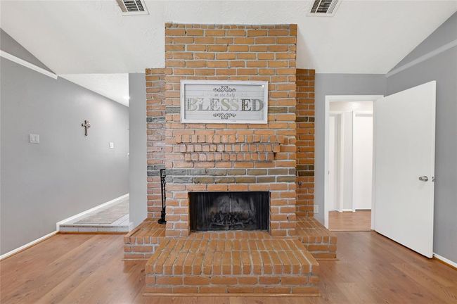 Cozy living room with a charming brick fireplace, ideal for a welcoming atmosphere. | Image 5
