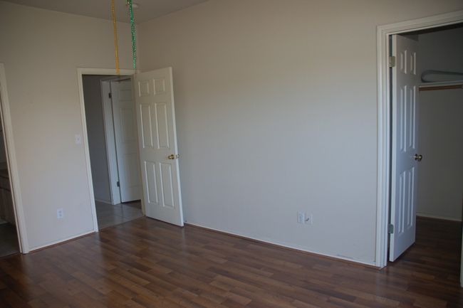 Unfurnished bedroom with dark wood finished floors, a closet, a spacious closet, and baseboards | Image 8