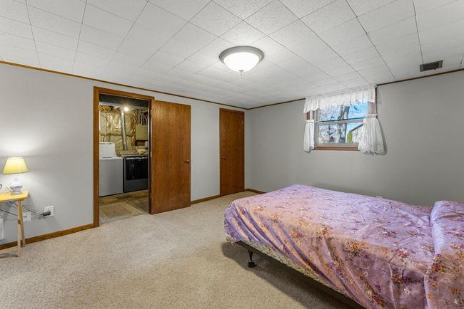 The lower-level third bedroom includes a closet with built-in shelving for optimal organization and soft carpeting for a cozy feel. | Image 15