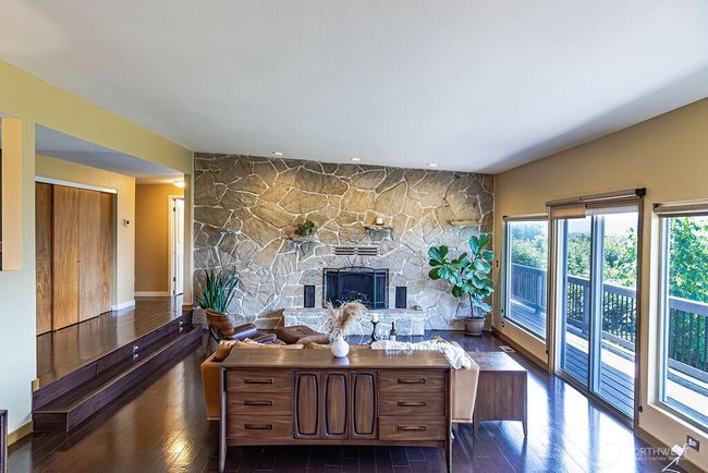 Gleaming engineered hardwood floors throughout main floor. Grand stone wall accentuates the wood burning fireplace. | Image 4