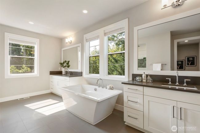 The spa-inspired primary bath offers a tranquil escape with a luxurious soaking tub framed by sun-filled windows, dual vanities with sleek quartz counters, and a soothing palette of soft neutrals. Thoughtfully designed for both relaxation and function, this serene space invites you to unwind in style. | Image 30