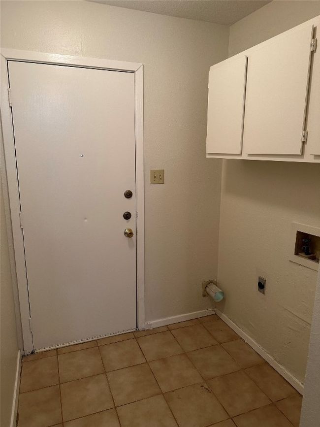 Laundry room featuring cabinet space, electric dryer hookup, hookup for a washing machine, and light tile patterned floors | Image 16