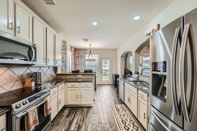 Kitchen featuring stainless steel appliances, dark countertops, a peninsula, arched walkways, and recessed lighting | Image 14