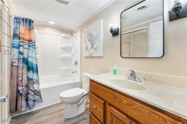 Bathroom with toilet, a textured ceiling, visible vents, and wood finished floors | Image 24