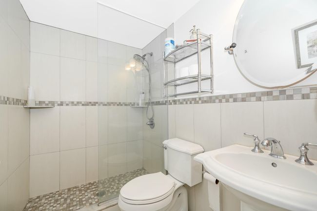 Full bath featuring a sink, toilet, tiled shower, and tile walls | Image 11