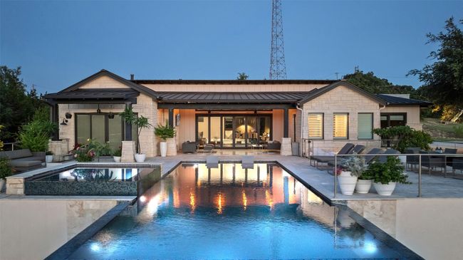Back of house featuring a standing seam roof, stone siding, a patio area, a metal roof, and an infinity pool | Image 8