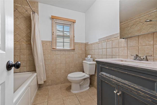Full bath featuring toilet, tile walls, wainscoting, tile patterned flooring, and vanity | Image 26