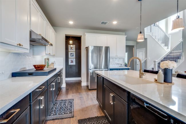 Kitchen with white cabinets, under cabinet range hood, a sink, and freestanding refrigerator | Image 12