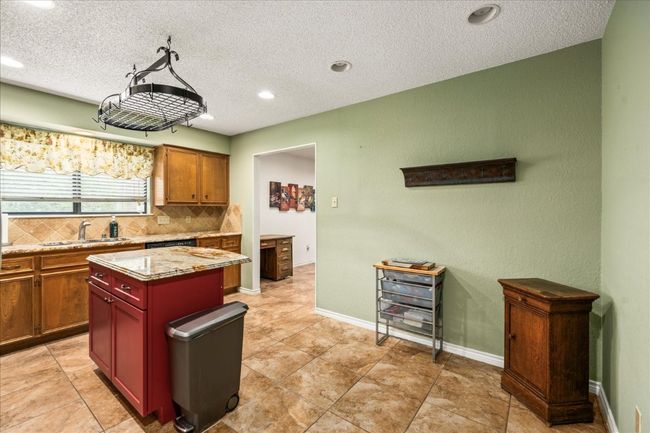 Kitchen with tasteful backsplash, a textured ceiling, recessed lighting, a center island, and light stone countertops | Image 16