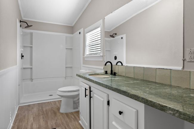 Full bathroom with a shower, wood finished floors, vanity, crown molding, and wainscoting | Image 24