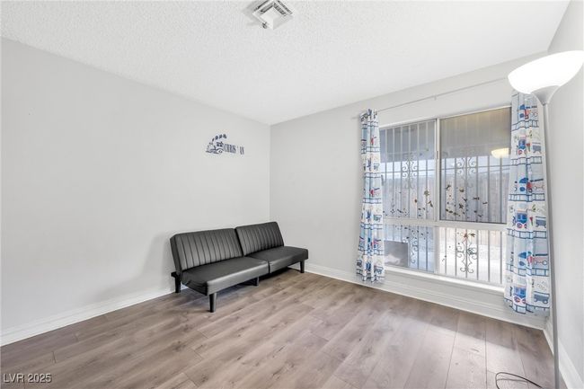 Living area featuring a textured ceiling, visible vents, wood finished floors, and baseboards | Image 11