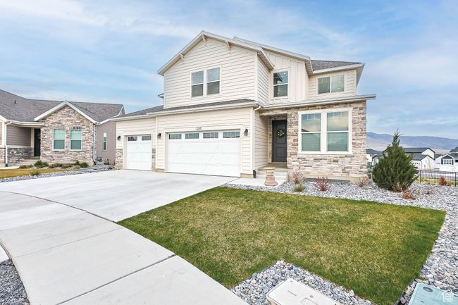 View of front facade featuring stone siding, an attached garage, driveway, and a front yard | Image 48