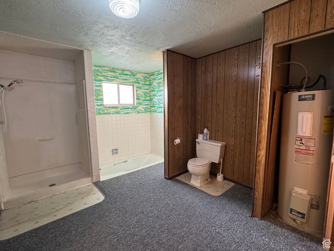 Bathroom featuring water heater, toilet, a textured ceiling, a shower, and a tub | Image 14