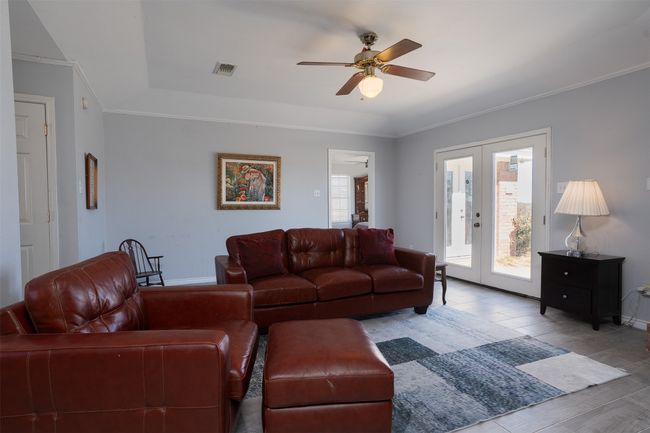 Living room featuring ornamental molding, a ceiling fan, baseboards, wood finished floors, and french doors | Image 8