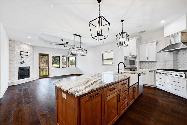 Kitchen with dark wood-style flooring, appliances with stainless steel finishes, wall chimney range hood, open floor plan, and backsplash | Image 11