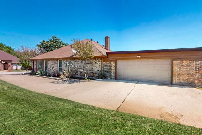 Ranch-style house with brick siding, a chimney, an attached garage, and concrete driveway | Image 37