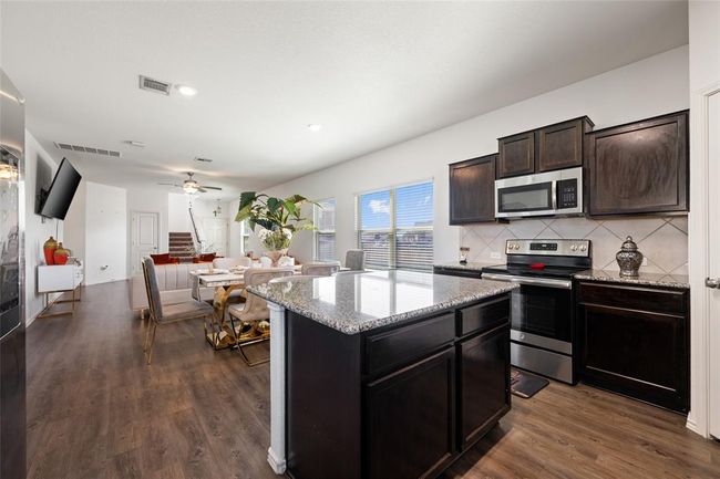 Kitchen with appliances with stainless steel finishes, light stone counters, ceiling fan, dark wood-style flooring, and recessed lighting | Image 8