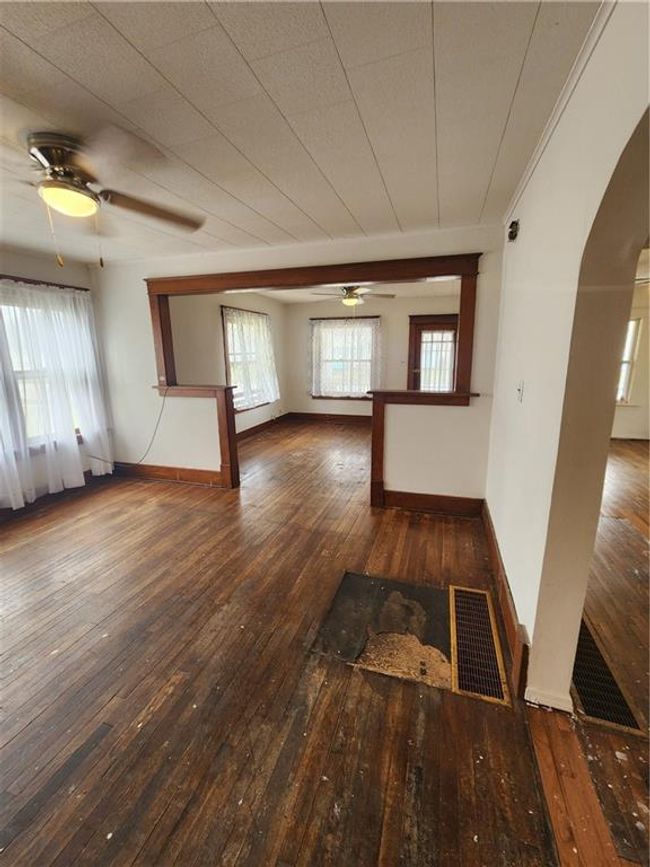 Empty room with visible vents, arched walkways, hardwood / wood-style flooring, and a ceiling fan | Image 13